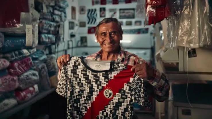 Un commerçant local brandit fièrement le maillot aux 1000 sponsors